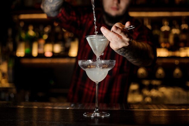 Barman die verse Margarita-cocktail gieten in een cocktailglas
