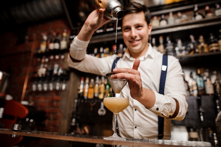 Foto barman giet een cocktail in het glas en glimlacht
