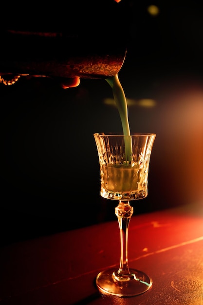 Barman giet een gemengde alcoholische cocktail uit een shaker in een glas Sfeervol warm licht Alcoholcocktail mengen in nachtclub pub restaurant