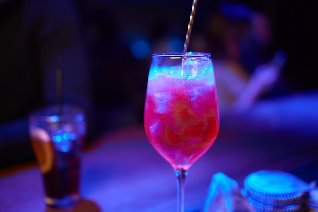 Barman giet roze cocktail in martini glas met flair
