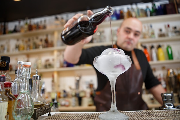 Barman giet wijn in het glas met gigantisch ijs, groothoekbeeld.