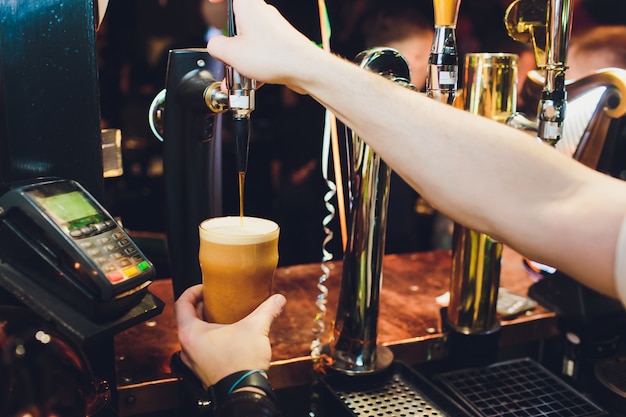 Barman gieten van kraan vers bier in het glas in de pub.