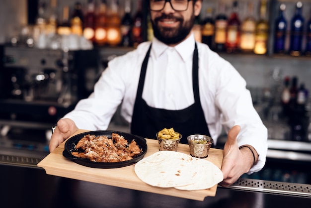 The barman gives food to customers order.