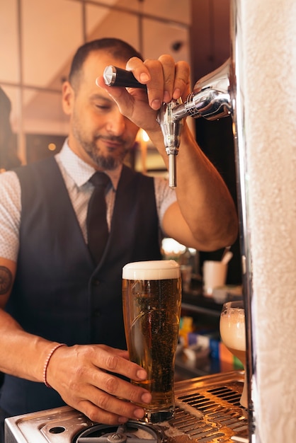パブで提供するドラフトラガービールを注ぐビールの蛇口でバーテンダーの手