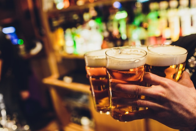 Mani del barista versando una birra chiara in un bicchiere.