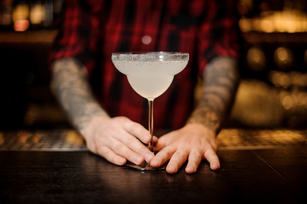 Barman holding a fresh Margarita cocktail in a cocktail glass