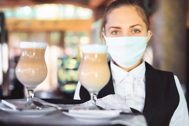 Barman in een medisch masker en handschoenen met latte koffie