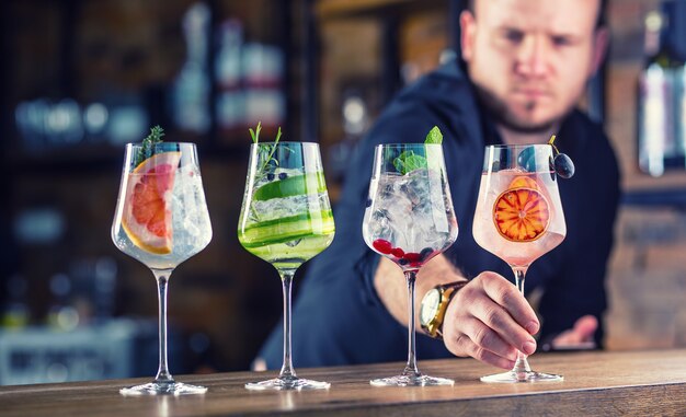 Barman in pub of restaurant bereidt een gin tonic cocktaildrankjes in wijnglazen.