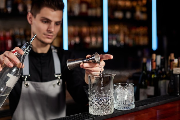 Barman in schort voegt ingrediënt toe aan glas.