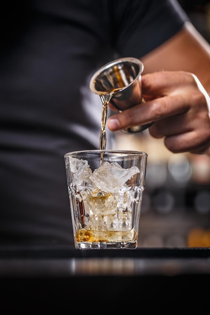 Barman is pouring alcohol from a jigger