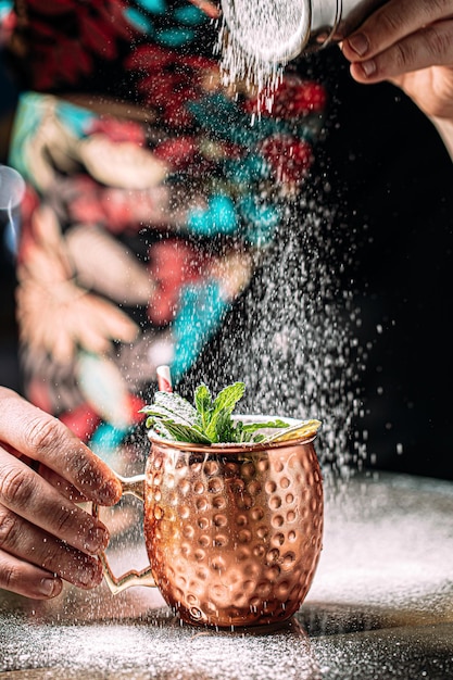 Barman maakt cocktail in koperen mok met suiker