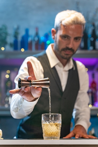 Foto barman maakt cocktails in een nachtclub, voegt ingrediënten toe en creëert deskundige dranken op de bar.