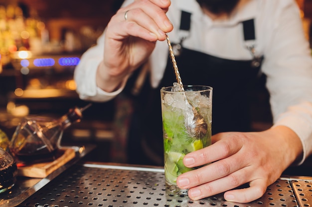 Barman makes a cocktail on the bar in the restaurant.