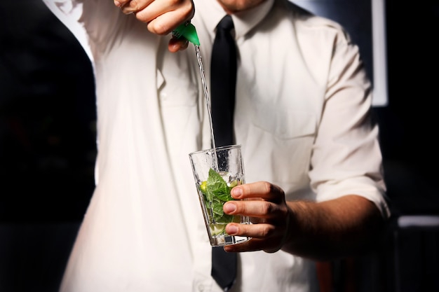 Barman making drink with mint and ice