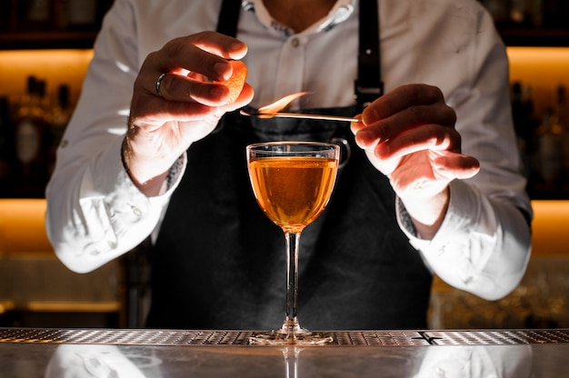 Barman making a fresh alcoholic cocktail with smoky note