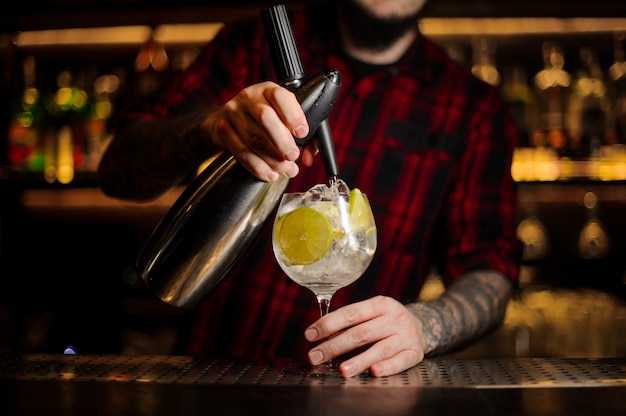 Barman making a fresh sour cocktail with lime using professional equipment on the bar counter