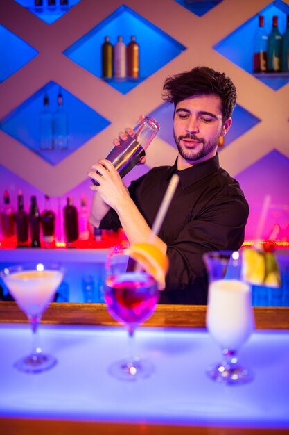 Barman met cocktailshaker op toog