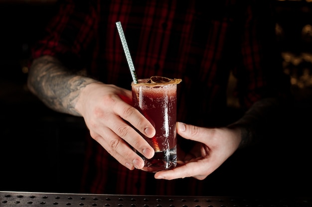 Barman met een Sippy Cup-cocktail in het glas met een gedroogde sinaasappel op de toog