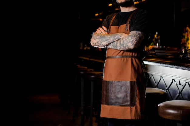 Barman met tatoeage op handen gekleed in bruine schort