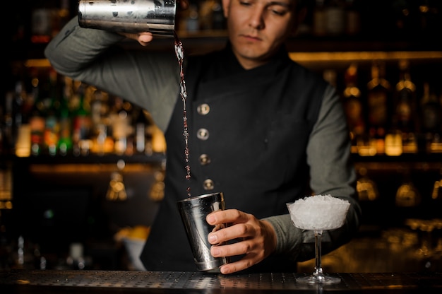 Barman mixing drinks for making a cocktail with campari