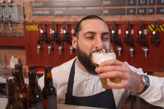 Barman nipt heerlijk bier, ogen sluiten van plezier