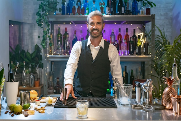 Foto barman portret in een wit hemd en zwart schort glimlachend naar de camera op een feestje in een nachtclub