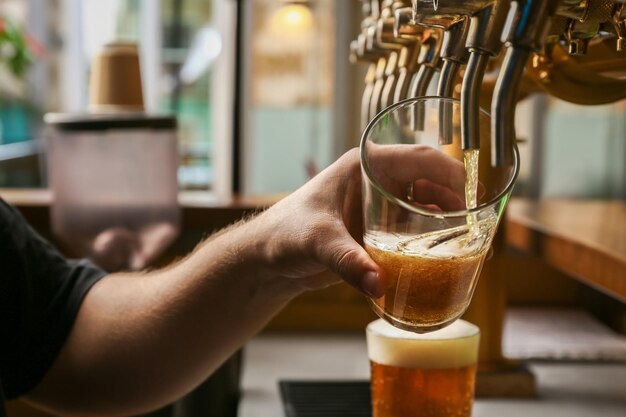 Photo barman pouring fresh beer in glass closeup