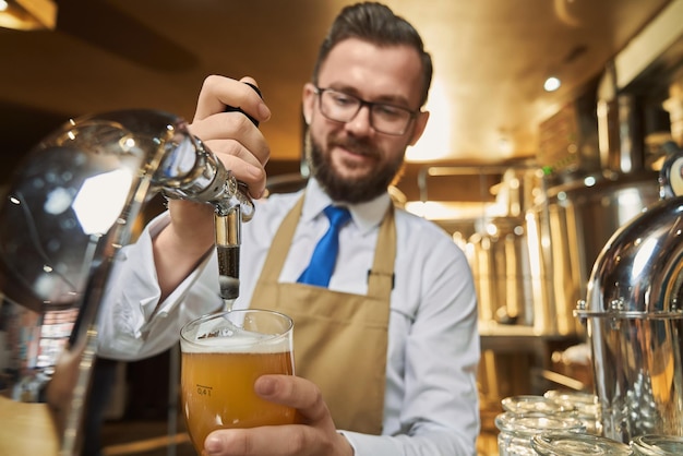 Barman pouring lager beer in cold glass