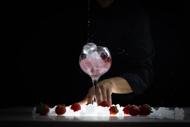 Foto barman preparando un gintonic de frutos rojos donde destacan las fresas arandanos o las frambuesas