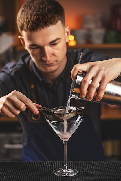 Barman preparing and pouring pink cocktail