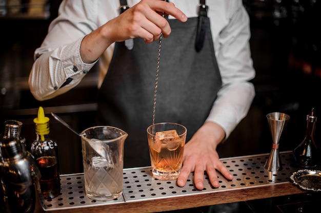 Barman roeren cocktail in het sierlijke glas op de toog