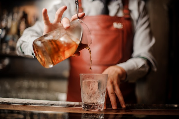 Barman's hands in bar interior making alcohol cocktail.