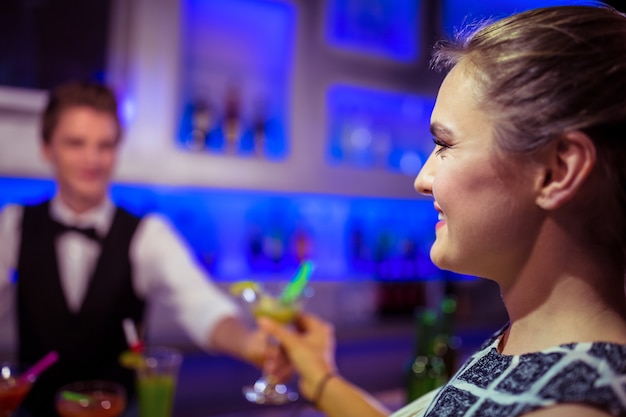 Barman serveert cocktail aan vrouw