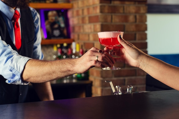 Barman serveert cocktaildrank voor klant aan de bar