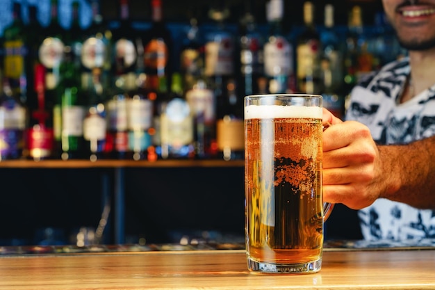 Barman serves glass of cold beer at bar counter in pub