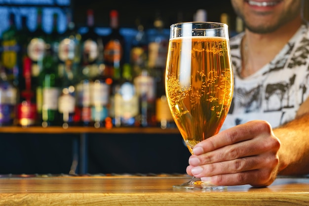 Barman serves glass of cold beer at bar counter in pub