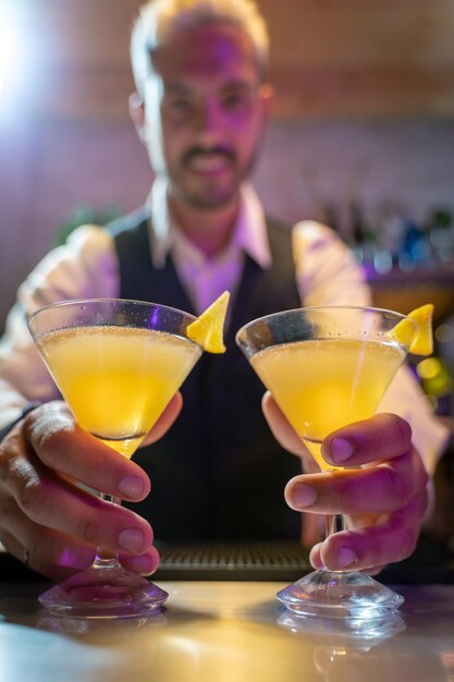 Photo barman serves two cocktails on the bar counter in the nightclub