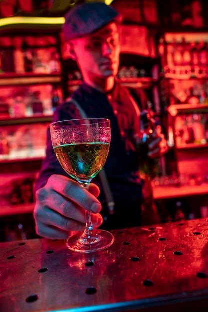 Barman stelt alcoholische cocktails, shots, drankjes voor aan gasten in veelkleurig neonlicht