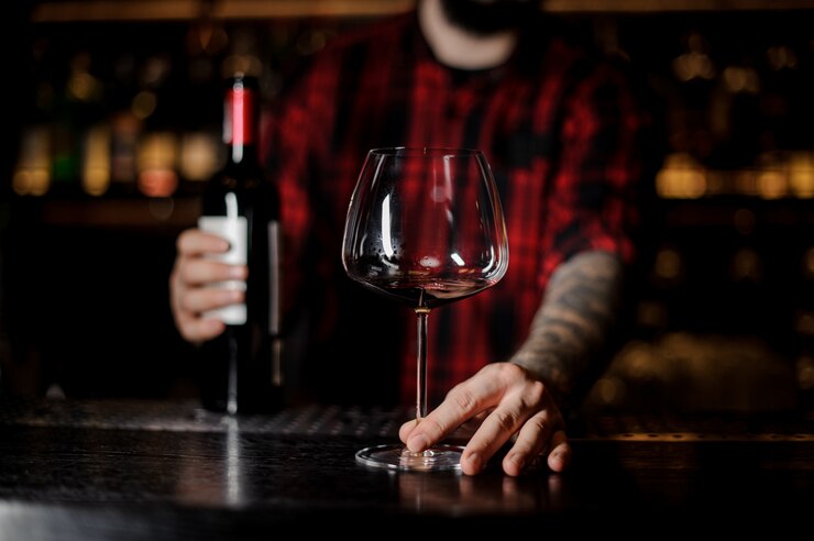 Photo barman with an empty burgunya glass and a bottle of red wine