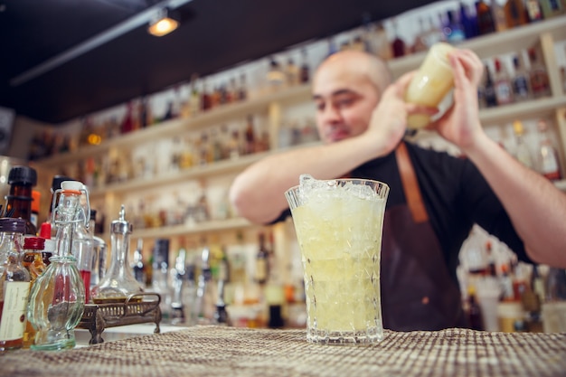 Barman at work. Shaking cocktail in shake.