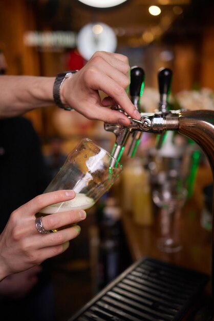 Barmanhand bij biertap die een tapbier in glas schenkt dat in een restaurant of pub wordt geserveerd