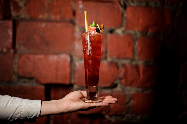 Barmanhand die een glas verse die cocktail van de zomerkeuken houden met aardbei en munt wordt verfraaid