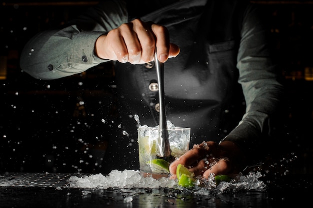 Barmanhand die vers sap van kalk drukken die caipirinha-cocktail maken