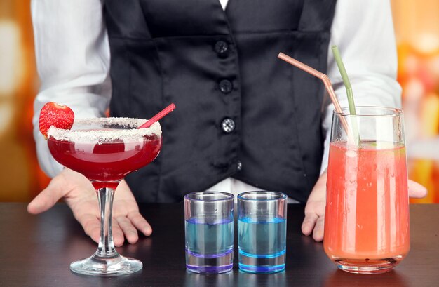 Barmen making tasty cocktails on bright background