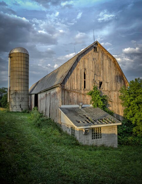 Photo barn on field by building against sky