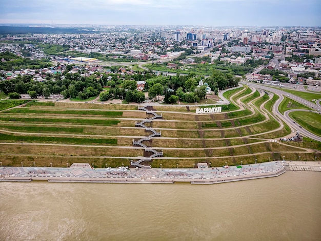 Photo barnaul, russia. description in russian of barnaul at the entrance to the city. highland park and a new embankment is the top view in summer