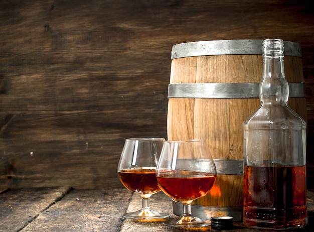 barrel with glasses of French cognac. On a wooden background.