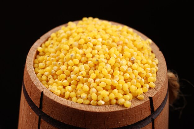 Barrel with millet on a black surface closeup