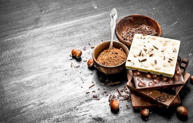 Barrette di diversi tipi di cioccolato con cacao in polvere. sulla lavagna nera.