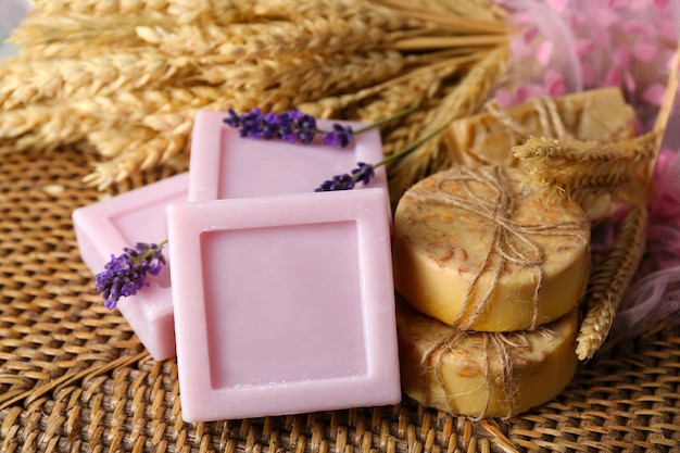 Bars of natural soap on wicker mat on light background